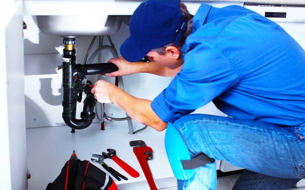 plumber repairing sink with tools